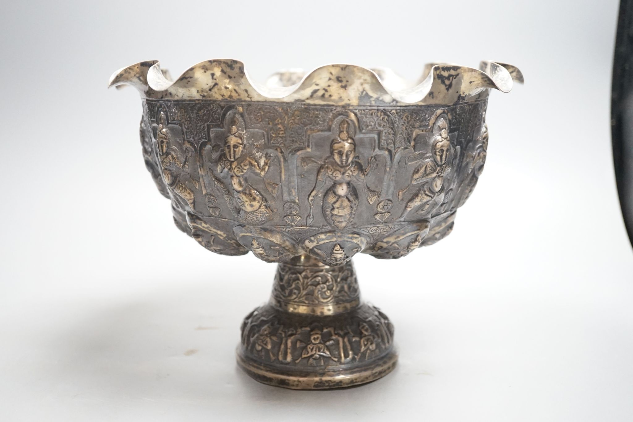 A late 19th century Burmese embossed white metal pedestal bowl, with wavy border, diameter, 27.2cm, 20.5oz.